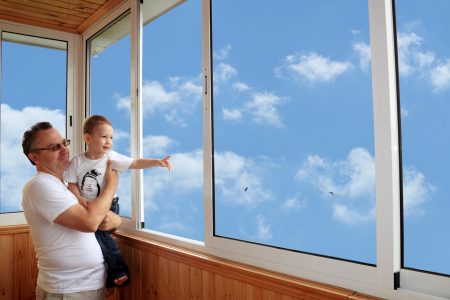 Grandson and grandfather standing on balcony and looking at the sky